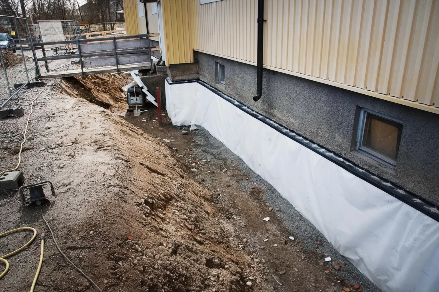 Uppgrävt runt flerbostadshus för dränering.